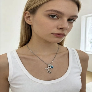 Close-up of elegant silver necklace featuring blue gemstone pendant on a female model