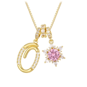 Macro detail of gold letter O pendant and pink snowflake charm with pavé zircon settings