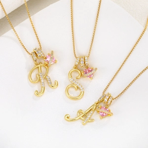 Detailed close-up of gold-plated letter pendants with pink heart stones and pavé crystals