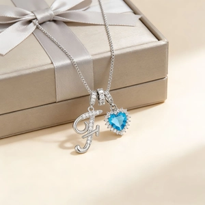 Silver letter F and blue heart gemstone pendant necklace displayed on a luxury gift box