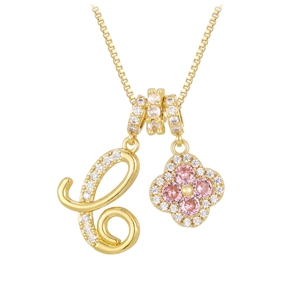 Macro shot of gold necklace with rhinestone letter C and pink clover pendants