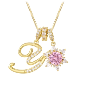 Macro detail of gold initial V necklace with pink gemstone flower and pavé zircons