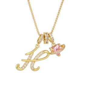 Close-up of gold letter H pendant and pink heart saturn charm on a delicate cross chain