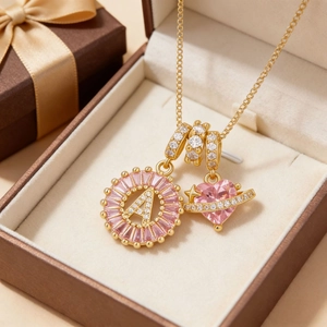 Collar dorado con colgante letra A de circón rosa y dije de corazón saturno en caja