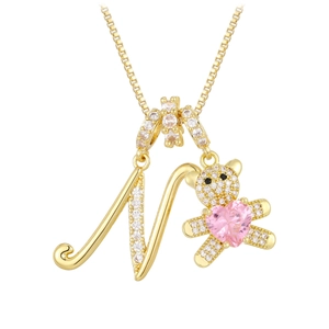 Macro shot of gold necklace with letter N and teddy bear pendant with pink heart stone