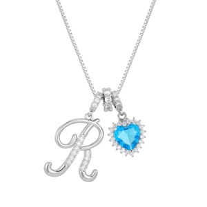 Macro shot of silver initial R pendant with blue heart sapphire and sparkling zircons