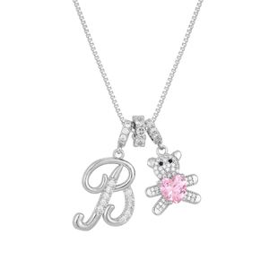Macro detail of silver necklace featuring letter B and bear with pink heart crystal