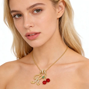 Collar de cerezas doradas con colgante letra R de cristal puesto en una modelo