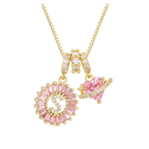 Detalle de collar dorado con colgante letra S, corazón de circón rosa y amuleto estrella