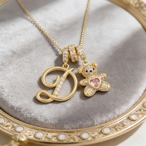 Gold bear and zircon letter D pendant necklace set on a luxury grey velvet tray