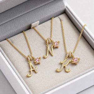 Collana con lettera dorata con cristalli bianchi e cuore rosa in una scatola per gioielli