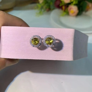 Vue macro d'une boucle d'oreille halo ronde avec pierre jaune-vert et zircons
