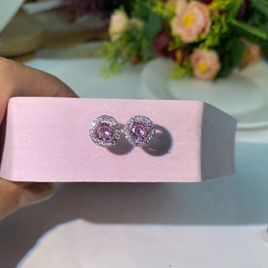 Détail de boucles d'oreilles en argent avec zircon rose et halo de diamants sur socle