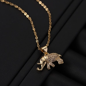 Macro view of gold elephant pendant with white zircon stones on a black leather stand