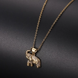 Close-up of golden elephant pendant with shimmering zircon pavé on a black background