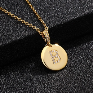 Vista macro del colgante dorado con letra 'B' y micropavé de circonitas cúbicas