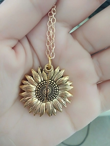 Détail d'un collier médaillon de tournesol doré aux pétales superposés à la main