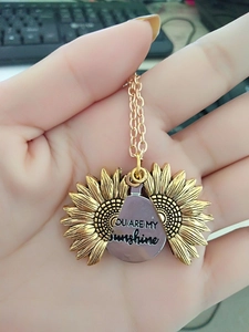Détail d'un pendentif tournesol ouvrant avec gravure You Are My Sunshine au milieu