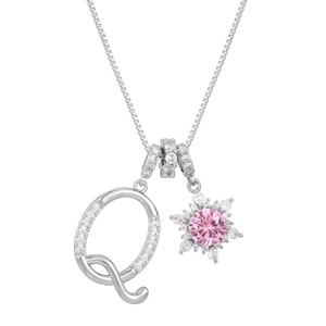 Macro shot of silver letter Q and snowflake pendant with a central pink gemstone