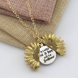 Gros plan du collier médaillon tournesol avec gravure inspirante sur la plaque interne