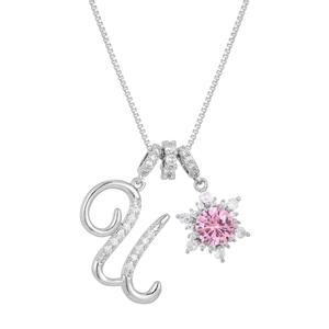 Macro detail of silver necklace with pavé letter U and snowflake pendant with pink stone