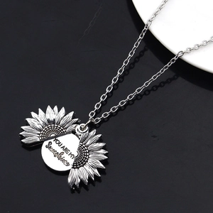 Détail du médaillon tournesol ouvrant avec gravure You Are My Sunshine sur collier