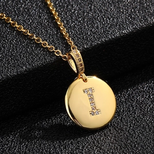 Primer plano de colgante dorado con letra I y circonitas engastadas en pavé