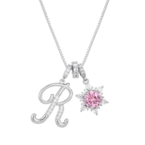 Macro detail of silver necklace with crystal letter R and pink gemstone snowflake pendant