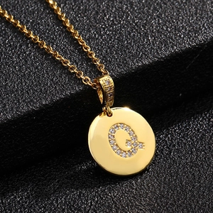 Detalle del colgante letra Q dorado con incrustación de circonita en fondo negro