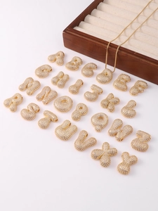 Detail of 26 chubby gold letters with white zircons on a white jewelry display