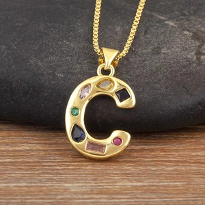 Detalle de un colgante letra C bañado en oro con incrustaciones de circonitas de colores