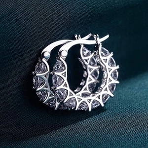 Silver-colored copper hoop earrings with pavé-set zircons on dark green texture fabric