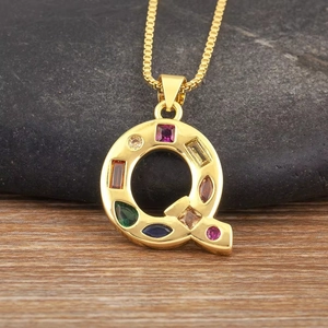Primer plano del colgante letra Q con circonitas de colores en cadena dorada