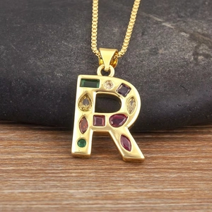 Primer plano del colgante letra R con cristales de colores sobre fondo de piedra