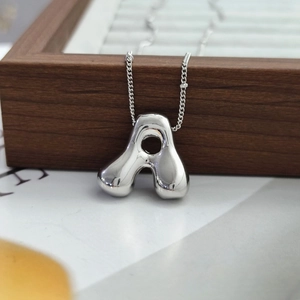 Macro shot of 3D balloon style letter A pendant on a thin silver chain necklace