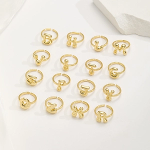 Collezione di anelli regolabili placcati oro con lettere a bolla su fondo bianco