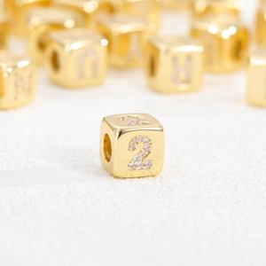 Vista macro di una perla quadrata con numero placcata oro 18k e zirconi per gioielli DIY