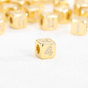 Macro di una perla a cubo placcata oro 18k con un numero quattro scintillante in strass