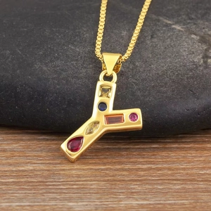 Vista macro del colgante letra Y dorado con circonitas de colores sobre fondo piedra