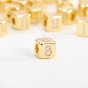 Vista macro di una perla a cubo placcata oro 18k con numero 8 in zirconia per gioielli DIY