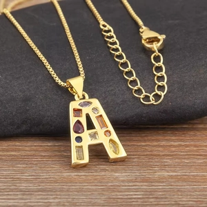 Collar dorado con colgante de letra A y circonitas multicolores sobre piedras negras