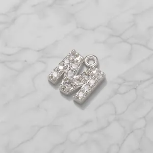 Detailed close-up of a zircon-set silver letter M pendant with 7mm width and 8mm length