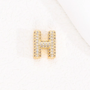 Primo piano del ciondolo lettera H placcato oro 18K con micro-pavé di zirconi scintillanti