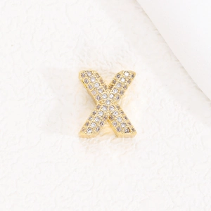 Macro del ciondolo a lettera X placcato oro 18K con pavé di pietre di zircone brillanti