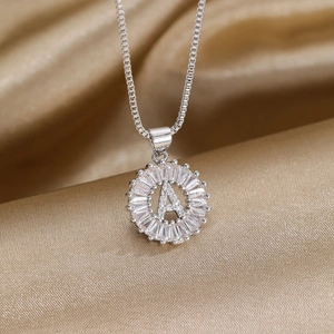 Détail macro du pendentif lettre A serti de zircons sur chaîne box et soie champagne