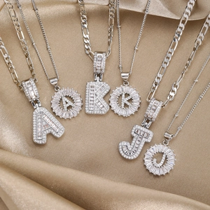 Iced out 18k gold plated copper letter pendants with zircon on champagne silk background