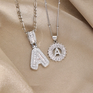 Iced-out 18k gold plated letter A pendants with baguette zircons on luxury satin background