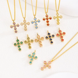 Détail de pendentifs croix dorés sertis de zircons cubiques colorés de forme carrée