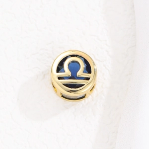 Detalle macro del colgante Libra dorado con circón azul oscuro y diseño calado