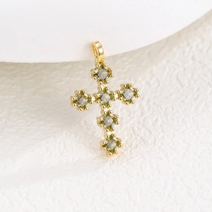 Vue détaillée d'un pendentif croix dorée avec six zircons carrés de couleur vert émeraude
